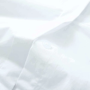Détail du tissu blanc et de la couture soignée du bouton sur cette chemise d'été