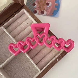Détail d'une grande pince à cheveux rose vif avec un design de chaîne en forme de cœur