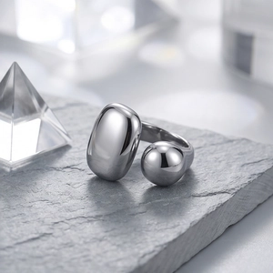 Minimalist silver open geometric ring with pebble and sphere ends on stone surface
