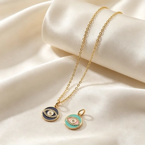 Detail of gold evil eye pendants with blue and green enamel and sparkling zircons