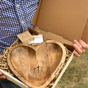 Macro shot of handcrafted heart-shaped wooden prayer bowl with engraved crosses in a gift box