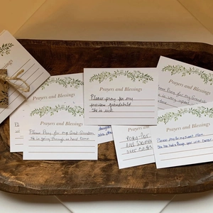 Close-up of heart prayer blessing cards with botanical designs in a rustic wooden tray