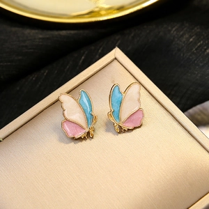 Macro shot of colorful butterfly stud earrings with gold outline on silk background