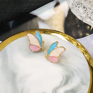 Detailed view of colorful butterfly earrings on a marble tray with golden finish