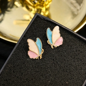 Macro shot of colorful enamel butterfly stud earrings with gold plating on black base