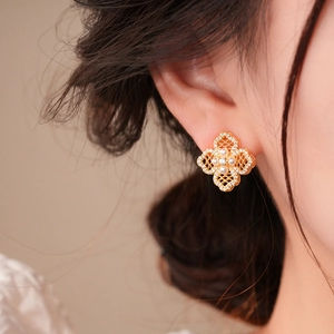 Detailed view of 18K gold clover earring with intricate hollow patterns and pearls