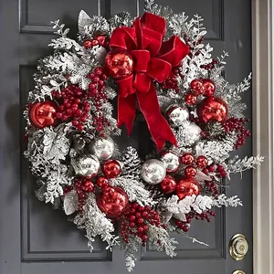 Elegant Christmas wreath with red ornaments and velvet bow on a dark wooden door