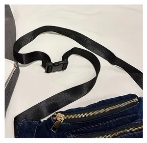 Detail of blue denim waist bag featuring double metal zippers and adjustable nylon strap