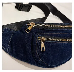 Detailed view of dual golden zippers and yellow stitching on dark blue denim waist bag