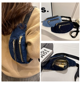 Detail of denim crossbody bag with dual gold zippers and adjustable black strap