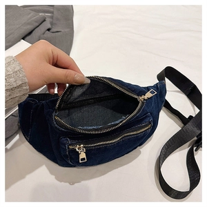 Macro view of blue denim fanny pack showing golden zipper detail and inner compartment