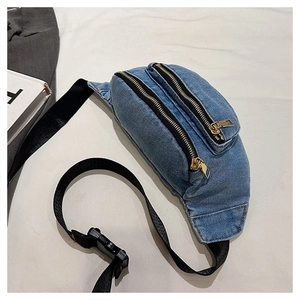 Close-up of light blue denim chest bag showing metal zippers and layered compartments