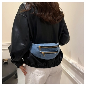 Detailed side view of blue denim waist bag with dual gold zippers worn by a model