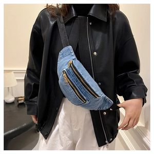 Detail of light blue denim waist bag featuring dual gold metal zippers and black strap