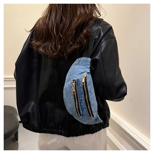 Detailed view of the blue denim chest bag with adjustable black strap and gold zippers
