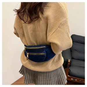 Detail of vintage washed denim fanny pack with golden zippers worn by a model