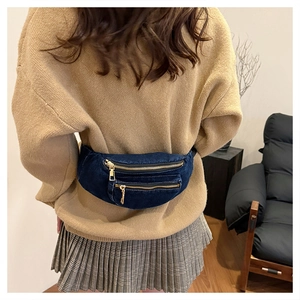 Close-up of deep blue washed denim waist bag with golden zippers and multi-pocket design