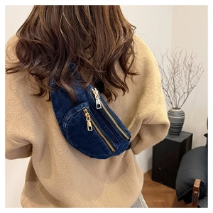 Detail of dark blue denim chest bag featuring gold metal zippers on a casual model