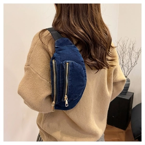 Rear view of a model wearing a deep blue denim chest bag with gold zippers and black strap