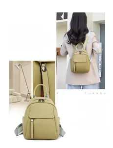 Detail view of olive green leather backpack with silver zippers and grey woven straps