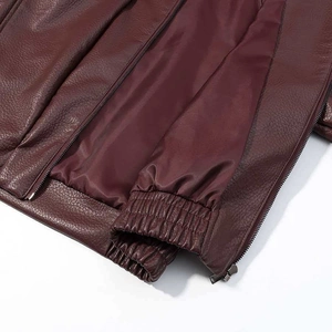 Detail of dark red leather bomber jacket showing elastic ribbed cuff and metal zipper