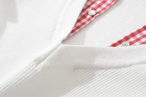 Close-up of white ribbed knit cardigan with V-neck and red gingham trim details
