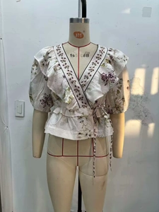 Détail d'un haut cache-cœur à fleurs avec col en V à volants et lien à la taille