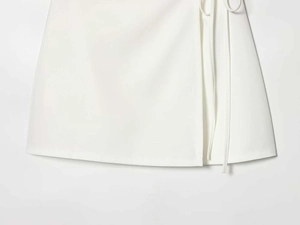 Close-up of white wrap midi skirt with tie-side waist and textured woven fabric