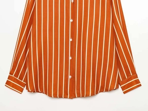 Detailed close-up of orange vertical stripes shirt with buttons and curved hemline