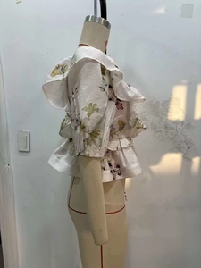Détail du chemisier floral à volants montrant des plis superposés et des manches bouffantes