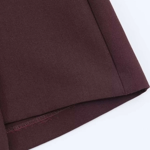 Dettaglio ravvicinato dell'orlo e delle cuciture dei pantaloncini a pieghe rosso vino