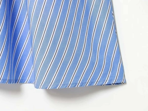 Detail of the blue and white striped fabric texture and stitched hem of the dress