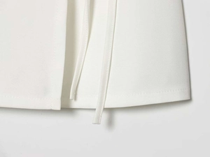 Close-up of the white blazer skirt set showing clean stitched edges and delicate ties