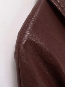 Nahaufnahme der dunkelbraunen Kunstlederjacke mit feiner Textur und Nähten