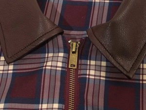 Dettaglio di giacca vintage a quadri con colletto in ecopelle marrone e zip in metallo