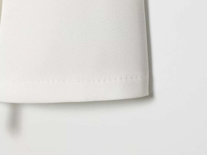 Close-up of high-quality sewing stitches on a minimalist white cotton suit set
