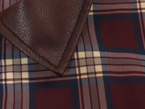 Dettaglio della texture in pelle marrone scuro con cuciture e tessuto a quadri