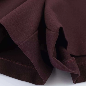 Dettaglio dei pantaloncini bordeaux a vita alta con cuciture overlock e trama in tessuto