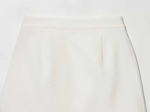 Detail view of the white tailored skirt featuring a clean waistband and premium stitching