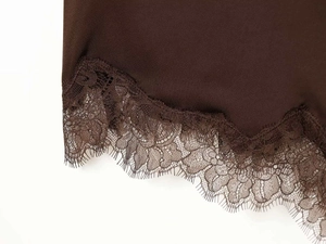 Detail of dark brown camisole hem featuring delicate floral lace trim and eyelash edges
