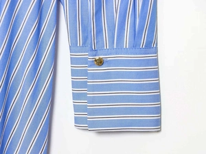 Detailed shot of striped shirt cuff featuring a contrast pattern and gold metal button