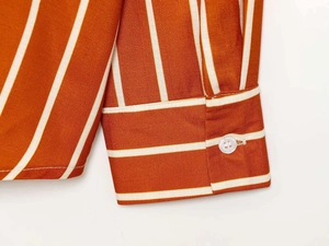 Detailed close-up of striped long sleeve shirt cuff with a white translucent button
