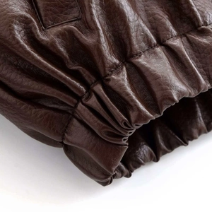 Détail macro du poignet élastique froncé sur une veste vintage en cuir marron foncé