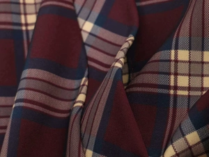 Dettaglio ravvicinato della trama del tessuto scozzese bordeaux e blu navy con quadri