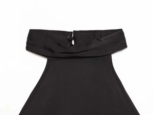 Detail view of the black halter neck collar with two button closures on woven fabric