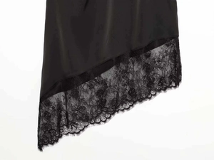 Detailed macro view of black satin fabric with delicate floral lace trim and eyelash edges