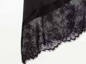 Detailed view of elegant eyelash lace trim and smooth black satin fabric on the hemline