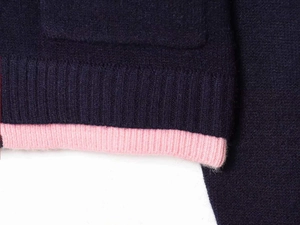 Detail shot of navy blue ribbed knit sweater hem with contrasting pink interior lining