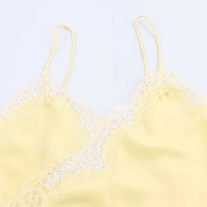 Detail view of smooth yellow satin camisole featuring delicate white floral lace trim