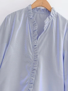 Detail of blue and white striped shirt featuring ruffle trim and a classic mandarin collar
